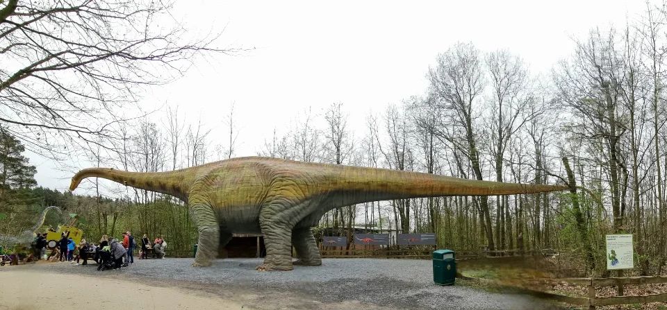 Ein Pflanzenfresser von gewaltigen Ausmaßen wird vo eoiner Besuchergruppe bestaunt.
