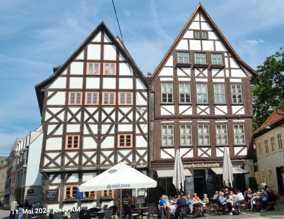 Fachwerkhäuser an einem belebten Platz mit Cafes und vielen Leuten